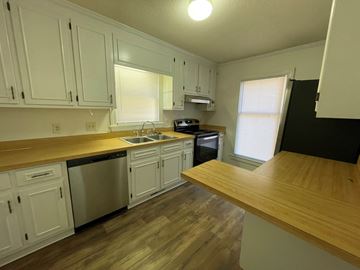 Wilson apartment for rent - A kitchen with white cabinets and a wooden counter.