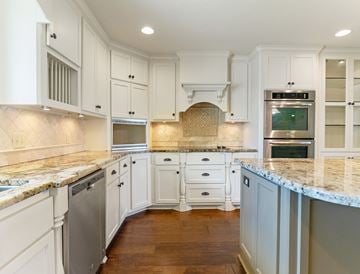 Bay City house for rent - A kitchen with white cabinets and a marble countertop.