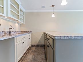 Bay City house for rent - A kitchen with a marble countertop and white cabinets.