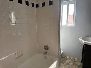 Washington apartment for rent - A white tiled bathroom with a tub, shower, and a window.