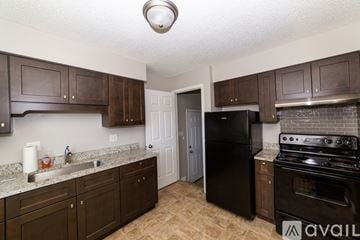 Des Moines house for rent - A kitchen with brown cabinets and a black refrigerator.