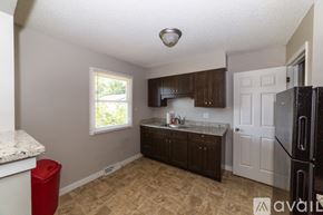 Des Moines house for rent - A kitchen with a black fridge, white oven, and brown cabinets.