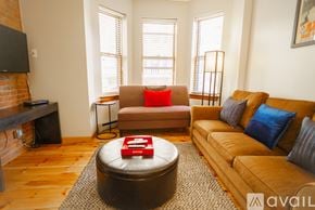 Boston apartment for rent - A living room with a brown couch, a red ottoman, and a television.