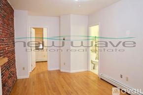 Boston apartment for rent - A room with a brick wall and wooden flooring is shown.