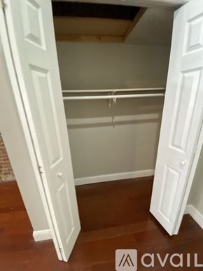 Boston apartment for rent - A white closet with a hanging rod and a door open.
