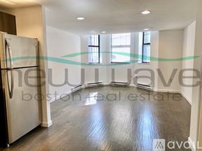 Boston apartment for rent - A room with a wooden floor and a refrigerator in it.