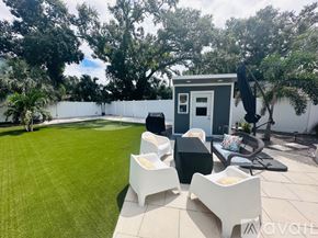 Gulfport house for rent - A backyard with a white fence, a small white building, and a black umbrella.