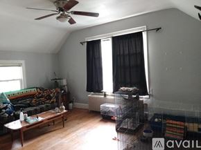 Mankato apartment for rent - A living room with a couch, a fan, and a window with curtains.