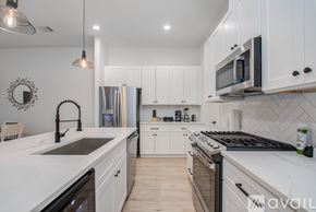 Houston townhouse for rent - A modern kitchen with white cabinets and a black stove top.