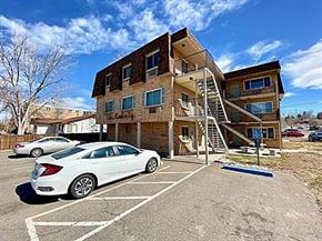 Englewood apartment for rent - A white car is parked in a parking lot in front of a two-story building.