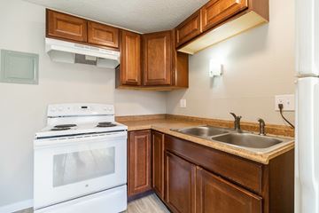 Englewood apartment for rent - A white stove is in a kitchen with brown cabinets.