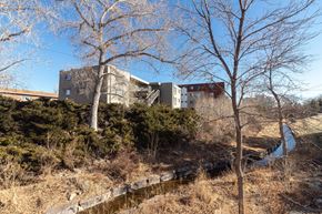 Englewood apartment for rent - A building is situated on a hill with a small stream running in front of it.