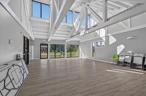 Merrillville apartment for rent - A spacious room with wooden floors and white walls, featuring a skylight and a row of chairs.