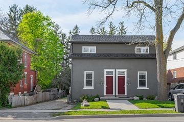 Guelph apartment for rent - A grey house with a red door stands on a street.