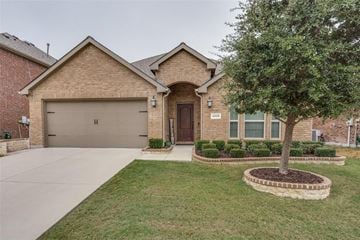 Frisco house for rent - A house with a brown garage door and a tree in front.