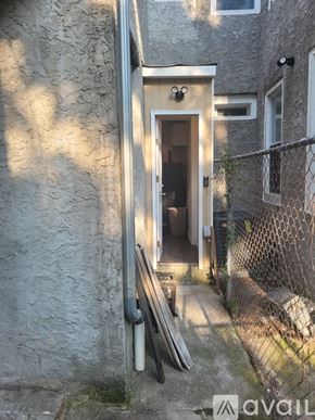 Philadelphia townhouse for rent - A small doorway in a grey building with a metal fence on the right side.