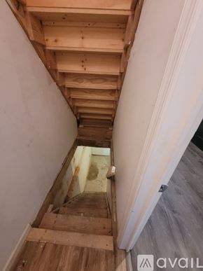 Philadelphia townhouse for rent - A wooden staircase with a white wall on the left side.