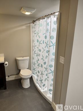 Dayton apartment for rent - A bathroom with a toilet, a shower curtain with sea creatures on it, and a shower head.
