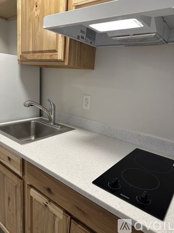 Palmer apartment for rent - A kitchen with a black stove top and wooden cabinets.