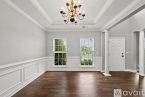 Morrisville house for rent - A large, empty room with a chandelier and a view of greenery outside the window.