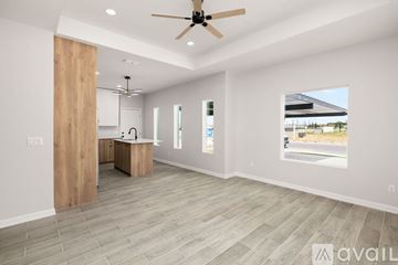 Edinburg apartment for rent - A spacious room with a ceiling fan and a kitchen area with a sink and cabinets.