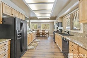 Breckenridge house for rent - A kitchen with a black fridge and wooden cabinets.