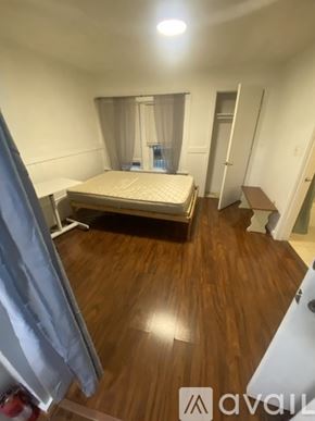 Boston apartment for rent - A bedroom with a bed, wooden floor, and a window with curtains.