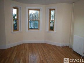Boston apartment for rent - A room with wooden floors and three windows.