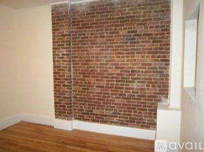 Boston apartment for rent - A room with a brick wall and wooden floor.