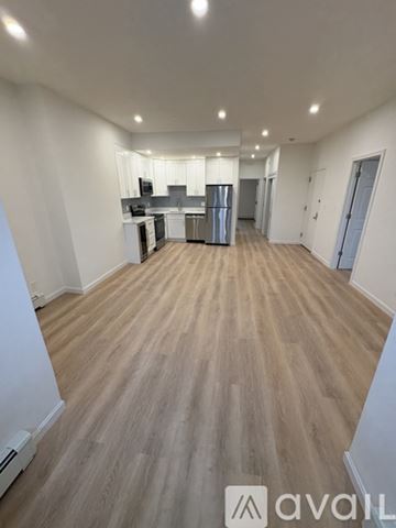 Boston apartment for rent - A spacious room with wooden flooring and a kitchen area in the background.
