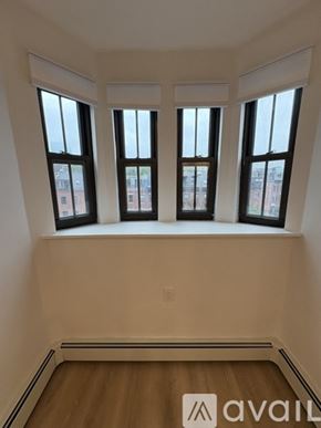 Boston apartment for rent - A room with three windows and wooden floors.