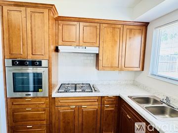 Sacramento house for rent - A kitchen with wooden cabinets and a white stove top.