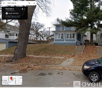 Omaha house for rent - A street view of a residential area with a blue house and a tree in the foreground.