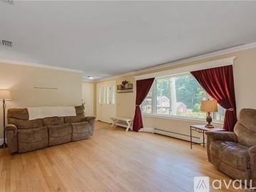 South Windsor house for rent - A living room with a brown couch and a white bed.