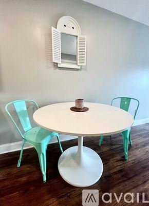 Washington condo for rent - A white table with a round base and a white chair with a green chair and a white wall with a mirror.