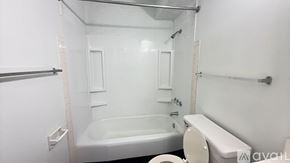 Muncie apartment for rent - A white bathroom with a bathtub, toilet, and sink.