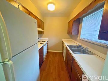 Muncie apartment for rent - A kitchen with a white refrigerator, wooden cabinets, and a sink.