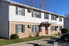 Muncie apartment for rent - A two-story house with a red door and a car parked in front.