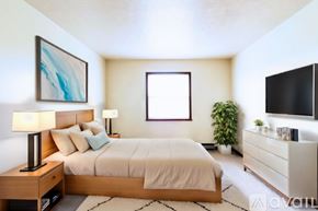 Lagrange apartment for rent - A well-lit bedroom with a large bed, a side table with a lamp, and a TV on the wall.