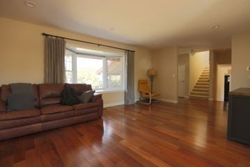 San Jose house for rent - A living room with a brown leather couch and wooden floors.
