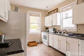 Highland Falls house for rent - A kitchen with white cabinets and a black countertop.