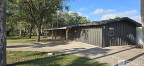 Donna apartment for rent - A grey building with a porch and a sign that says "available" in the front yard.