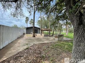Donna apartment for rent - A backyard with a concrete patio, a tree, and a wooden gazebo.