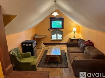 Traverse City house for rent - A living room with a green chair, a brown couch, and a television mounted on the wall.