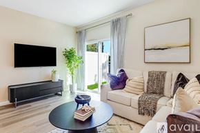 Orange Park townhouse for rent - A living room with a black sofa, a coffee table, and a flat screen TV mounted on the wall.