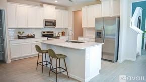 Orange Park townhouse for rent - A kitchen with white cabinets and a white island with two chairs.