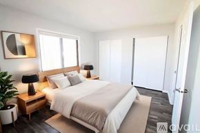 Milroy apartment for rent - A bedroom with a large bed, a nightstand with a lamp, and a plant.