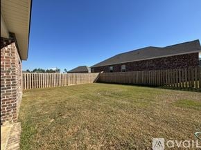 Biloxi house for rent - A grassy yard with a wooden fence and a house with a brick chimney.