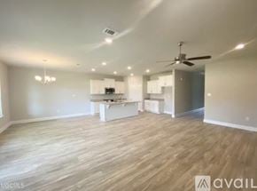 Biloxi house for rent - A spacious room with wooden flooring and a ceiling fan.