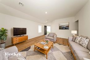 Tuttle house for rent - A living room with a grey couch, a wooden coffee table, a flat screen TV, and a potted plant.